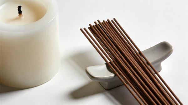 Incense vs Candles: What’s the Difference? A side-by-side comparison of natural incense sticks on a ceramic holder and a lit white candle, highlighting the different elements of modern self-care rituals.